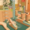 複雑に入り組んだボールのコース（ビー玉転がしのような装置）。段ボール風の素材で作られた斜面、らせん状のレール、リフト機構などが配置されており、複数の色のボールが